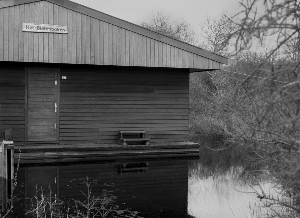 The shuttered front of a timber garden building with floodwater reaching its steps.